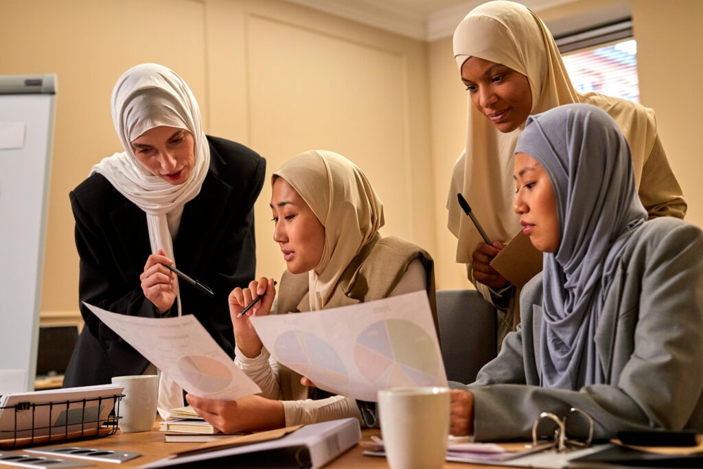 A group of Muslim women in hijabs having a productive meeting in an office setting.