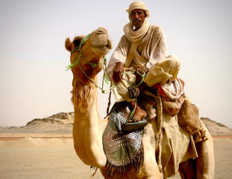 A nomadic man on a camel in the Sudanese desert, showcasing traditional attire.